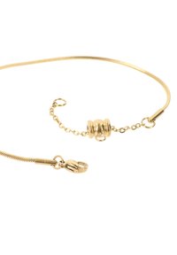 Bracciale in metallo dorato con un design flessibile e sottile, dotato di un clasp rotondo e catena regolabile. Texture liscia e finitura lucida.