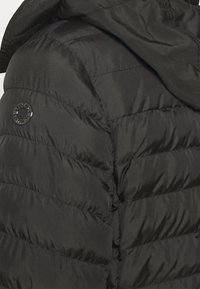 Chaqueta acolchada negra con capucha, con textura acolchada, parche de logotipo circular en la manga y material liso y elegante.