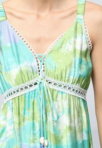 Robe d'été légère avec un motif tie-dye vert et bleu, une bordure en dentelle blanche et un cordon de serrage ajustable à la taille.