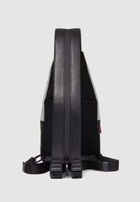 Zaino a tracolla nero e grigio con pannello posteriore imbottito, spallacci regolabili e tasca verticale con cerniera su uno sfondo chiaro uniforme.