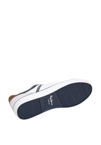 Sneaker biru navy dan putih dengan sol karet. Memiliki pola herringbone yang tertekstur, merek di sisi, dan aksen coklat di tumit.
