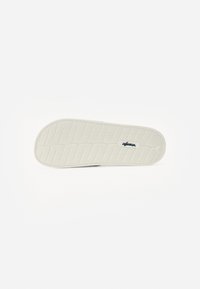 Talpă din cauciuc cu o suprafață texturată, albă și un model de striație. Prezintă brandingul "Wanderer" în albastru în interiorul talpii.