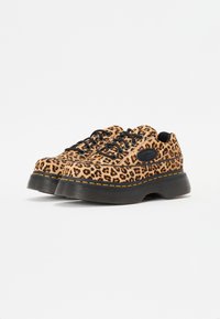 Zapatillas de plataforma con estampado de leopardo, cordones negros, una superficie texturizada y una suela negra gruesa acentuada con costuras amarillas.