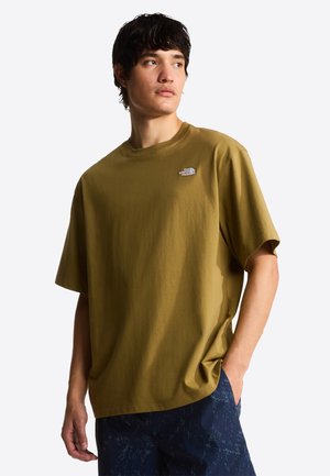 Oliwkowa bawełniana koszulka o luźnym kroju, z okrągłym dekoltem i logo The North Face na lewej piersi. Stylizowana z granatowymi, wzorzystymi szortami.