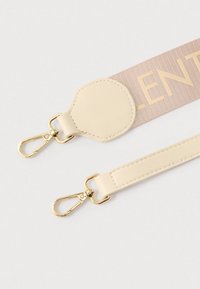 Bež tkaninski trak z napisom »VALENTINO«, z zlatimi kovinskimi sponkami in teksturiranim usnjenim poudarkom na enem koncu.