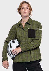 Grün kariertes Langarmhemd mit einer schwarzen Brusttasche, aus leichtem Stoff, kombiniert mit einem weißen Fahrradhelm.