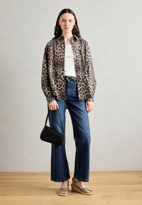 Leapardmønstret bomberjakke over en hvid skjorte, parret med højtaljede blå jeans og en sort taske. Ballett композиции med leopard mønster.