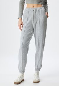Grijze sweatpants met een trekkoordtaille, geribbelde textuur, twee zijnaad en elastische boorden, gecombineerd met witte sneakers.
