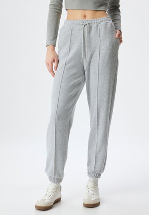 Grijze sweatpants met een trekkoordtaille, geribbelde textuur, twee zijnaad en elastische boorden, gecombineerd met witte sneakers.