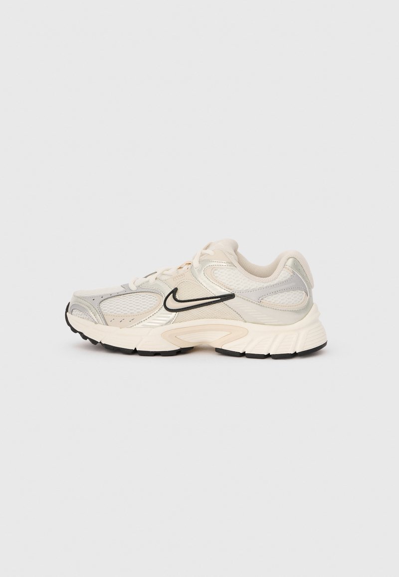 Light beige and white Nike running shoe with mesh panels, black swoosh logo, and thick cushioned sole on a plain background.