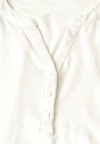 Bílá bavlněná košile Henley s V výstřihem, obsahující pět knoflíků a jemnou, hladkou texturu. Bez viditelných vzorů nebo akcentů.
