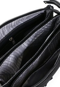 Black synthetic bag with multiple compartments, zip closures, and a gray patterned interior featuring text. Smooth texture and structured design.