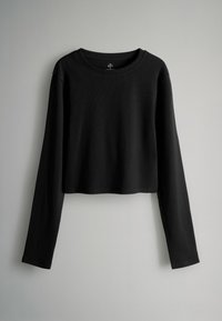 Melna garām piedurknēm kroptā kreklā ar ribota auduma struktūru, apaļu kakla izgriezumu un brīvu piegriezumu. Nav redzamu logotipu vai dekoratīviem elementiem.