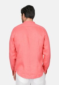 Camicia di lino corallo con maniche lunghe, polsini bottonati e colletto classico. Tessuto testurizzato con una vestibilità rilassata e orlo curvo.