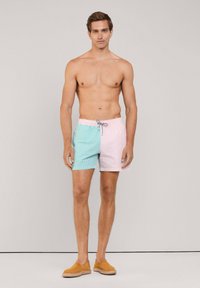 Zwemshorts in blauw en roze strepen, gemaakt van lichtgewicht stof, hebben een elastische tailleband met een trekkoord en zijn op dijhoogte.