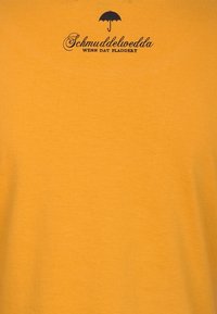 Bomull T-shirt i senapsgul med en svart paraplylogotyp och texten "Schmuddelwedda WENN DAT PLADDEBT." Korta ärmar, mjuk textur.