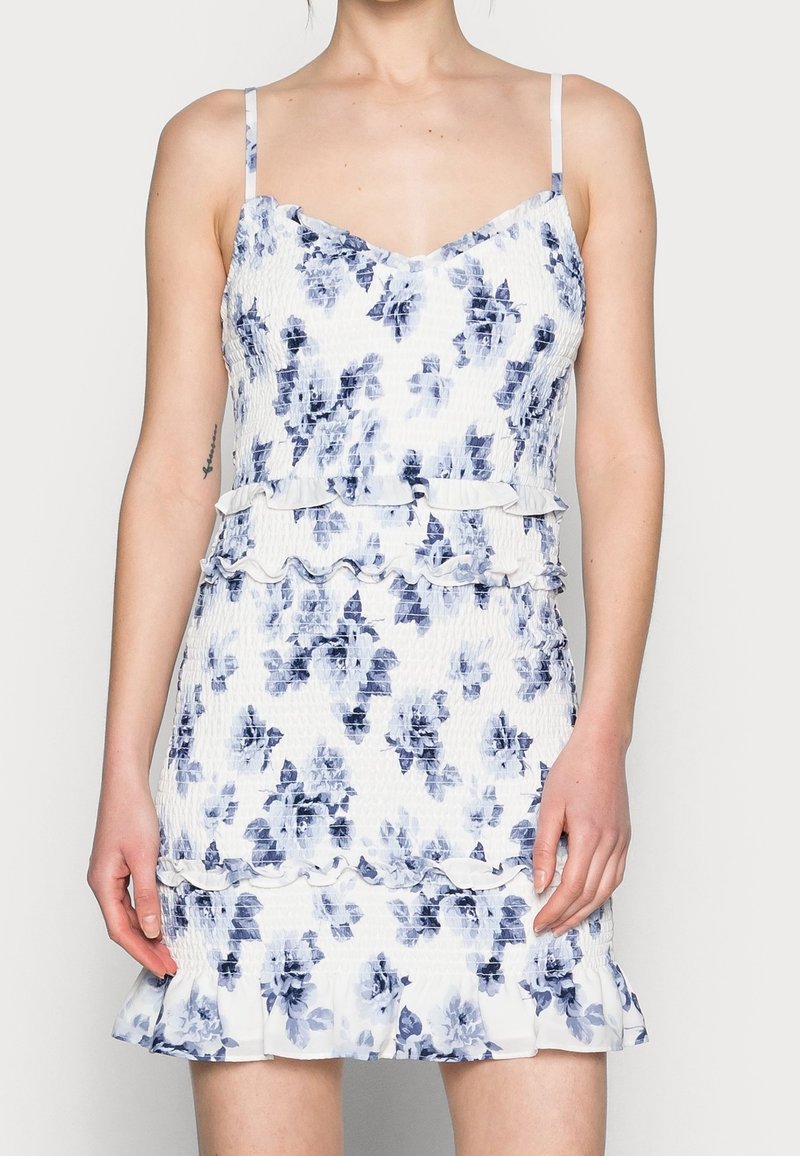 Květinové šaty s modro-bílým vzorem, přiléhavý korzet, volánkové detaily v pase a na lemu, tenká ramínka, strukturovaná tkanina.