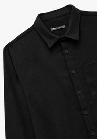 Camisa de franela negra con cuello puntiagudo, botones en el frente, un bolsillo de parche y una tela suave y texturizada. Diseño de ajuste regular.