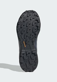 Außenschuhsohle mit einer schwarzen Gummifläche und einem strukturierten, multidirektionalen Profilmuster für verbesserte Traktion und Stabilität.