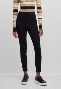 Zwarte high-waisted skinny jeans met een gladde textuur, voorzien van een sluiting met knoop aan de voorkant, twee zakken en een getailleerd ontwerp.