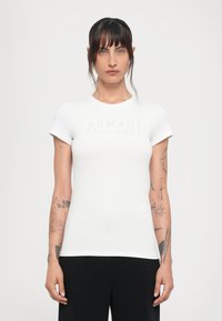 Witte aansluitende t-shirt met korte mouwen en een ronde halslijn, met een reflecterend "ARMANI EXCHANGE" logo op de borst.