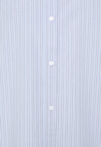Light blue, striped button-up shirt made of smooth fabric, featuring white buttons and vertical lines with contrasting darker stripes.