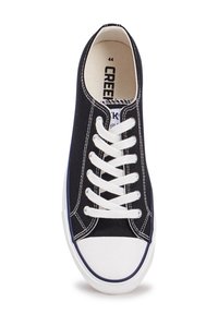 Baskets en toile bleu marine avec semelle en caoutchouc blanc, bout rond et lacets blancs contrastants. Caractéristiques de couture renforcée et logo sur la languette.