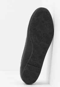 Semelle de chaussure plate noire avec motif cachemire texturé et petites formes de cœur, taille indiquée comme 37, sur fond blanc.