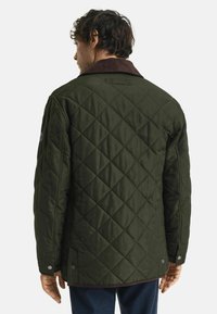 Donkergroene, gewatteerde jas met een bruine corduroy kraag en drukknoopsluitingen. Heeft een gestructureerd ruitpatroon en een relaxte pasvorm.