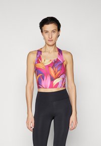 Top de sport floral court avec un design multicolore rose et orange, présentant un décolleté en scoop et des bretelles larges, associé à des leggings noirs ajustés.