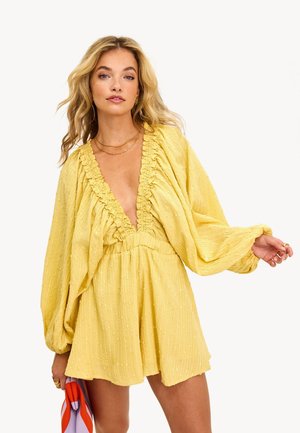 Robe jaune avec encolure froncée et longues manches bouffantes. Fabriquée dans un tissu texturé avec de subtils pois en relief. Coupe lâche, longueur au-dessus du genou.