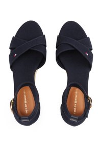 Infradito in tela navy con straps incrociati, fibbia in tonalità oro e soletta color tan. Presentano il marchio Tommy Hilfiger sulla soletta.