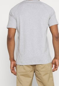 Grå kortärmad t-shirt med raglan-design. Mjuk textur, enkel passform och inga ytterligare mönster eller detaljer. Lämplig för avslappnad användning.