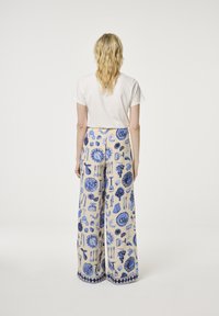 Wijde broek in crème stof met blauwe geïllustreerde patronen van voedsel en bestek, met een effen blauwe zoom en tailleband.