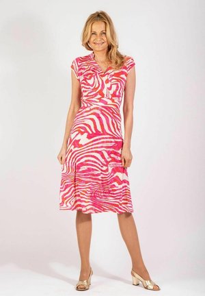 Rosa- und weiß gestreftes Kleid mit tailliertem Oberteil, kurzen Ärmeln, V-Ausschnitt und ausgestelltem Rock. Kombiniert mit goldenen offenen High Heels.