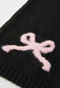 Black knit fabric featuring a soft, textured pink bow design. The bow is outlined with a fluffy, slightly raised finish.