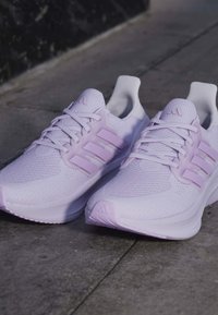 Двойка светлолилави маратонки Adidas с мрежести горни части и три странични ивици върху бетонна повърхност.