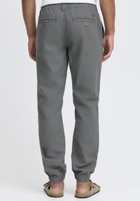 Pantalons de jogging légers grays avec une taille élastiquée, deux poches arrière et des poignets fuselés. Fabriqués à partir d'un tissu texturé.