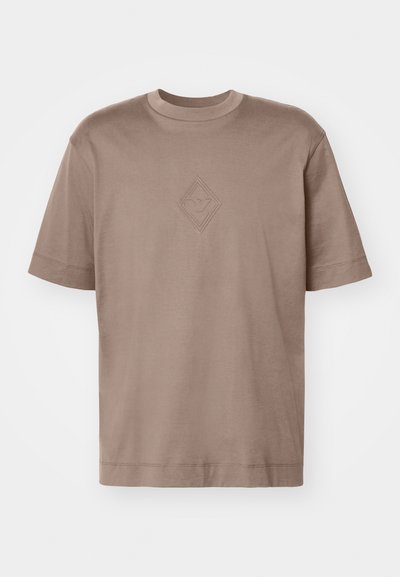 Camiseta de manga corta, color marrón claro, fabricada en algodón suave, con un logo de diamante en relieve centrado en el pecho. Diseño clásico de cuello redondo.