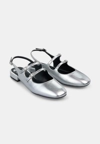 Chaussures slingback argentées métalliques avec un design à bout carré, deux fines sangles réglables sur le devant du pied et un petit talon carré.