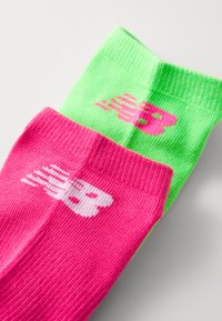 Fargerike bomullssokker med en grønn stripe og en rosa stripe, begge med et hvitt logodesign nær toppen. Myk tekstur og middels lengde.