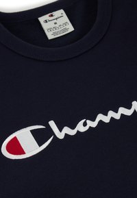 Sudadera de algodón azul marino con texto bordado en blanco "Champion" y acento rojo. Diseño de cuello redondo con cuello ribeteado estándar.