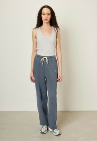 Svetlosivý tielkový top v kombinácii s voľnými tmavosivými teplákmi s šnúrkou v páse a detailom loga, doplnené sivými teniskami.