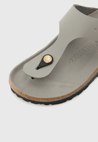 Gray thong sandal featuring a textured footbed and a black button accent. Cork sole with a black rubberized edge for grip.