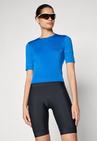 Blå cykeltröja med kort ärm, med en figurnära design och sydda detaljer, i kombination med svarta cykelshorts med en vadderad insats.