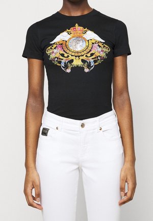 Czarna bawełniana koszulka z kolorowym wzorem graficznym przedstawiającym koronę, skrzydła i elementy kwiatowe. W zestawie z białymi jeansami.