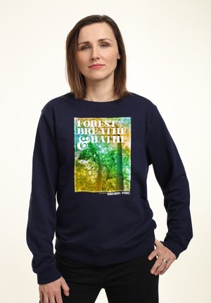 Felpa navy con una grafica vivace della natura che presenta alberi. Il testo recita "FOREST BREATHE & BATH," con una texture morbida e un fit rilassato.
