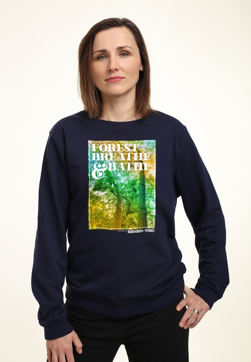 Felpa navy con una grafica vivace della natura che presenta alberi. Il testo recita "FOREST BREATHE & BATH," con una texture morbida e un fit rilassato.