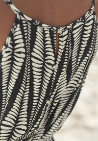 Black and white dress featuring a fern leaf pattern, with a keyhole back detail and decorative buttons along the opening. Soft fabric texture.
