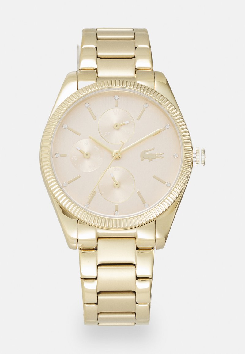 Reloj de tono dorado con esfera redonda, tres subesferas, acentos de diamante y una pulsera de metal pulido. El reloj presenta un bisel texturizado y un logotipo.